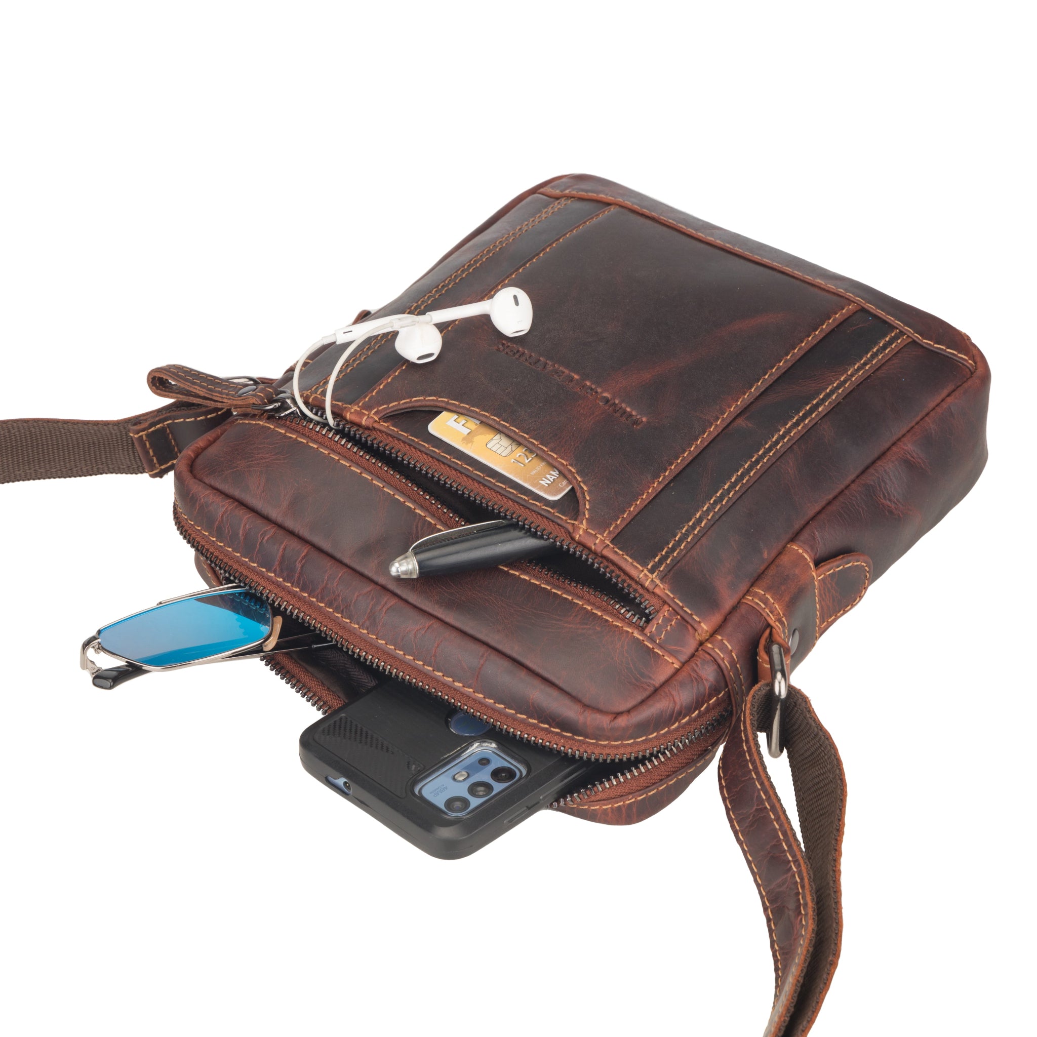 Brown Minori leather crossbody bag with various items inside on a white background