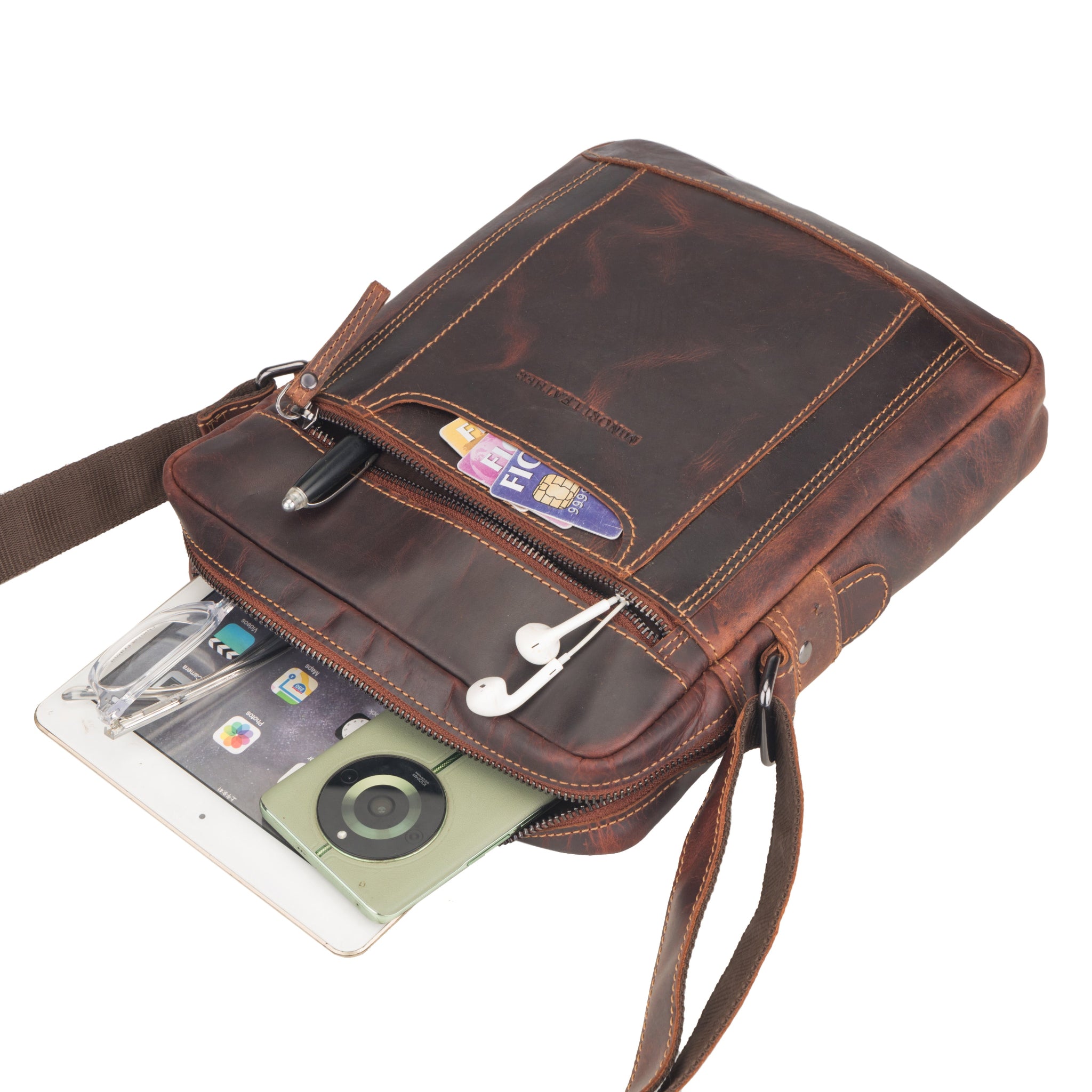 Brown Minori leather crossbody bag with a tablet and items inside on a white background