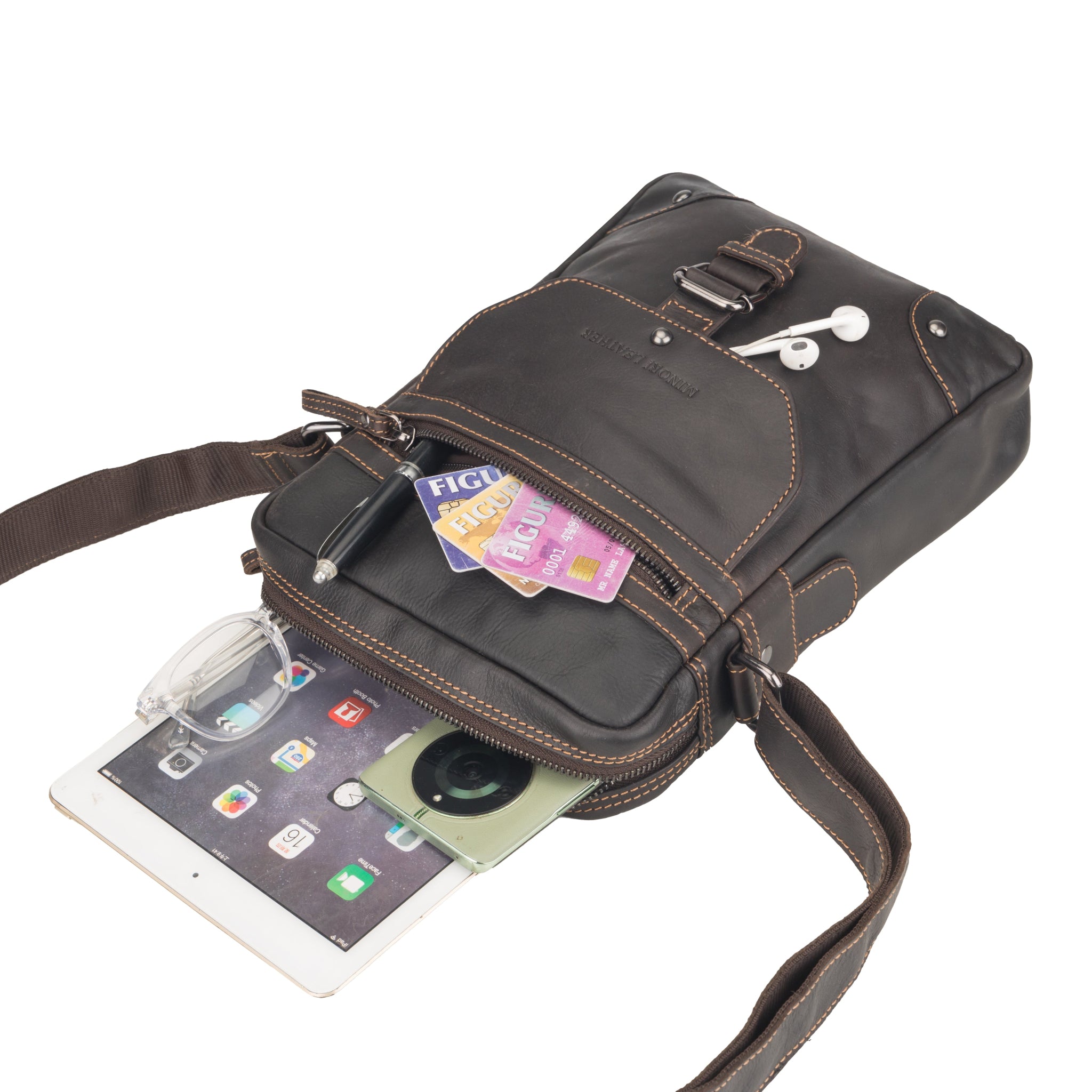 Brown Minori leather crossbody bag partially packed with an iPad, smartphone, glasses, cards, pen, and earphones in external compartments.