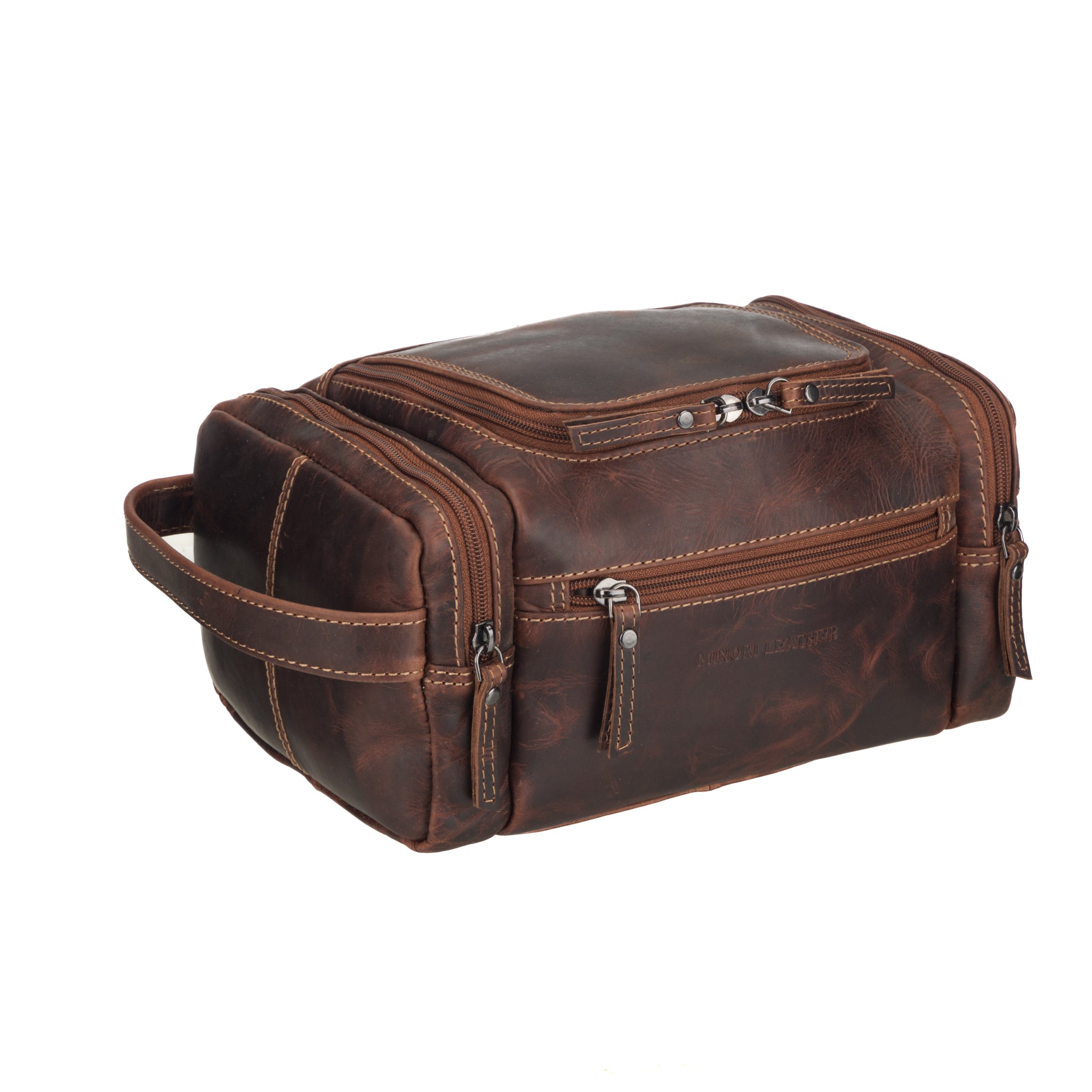 Angled front view of chestnut brown Minori leather toiletry bag showcasing side handle, front compartments, and vintage-style leather finish.