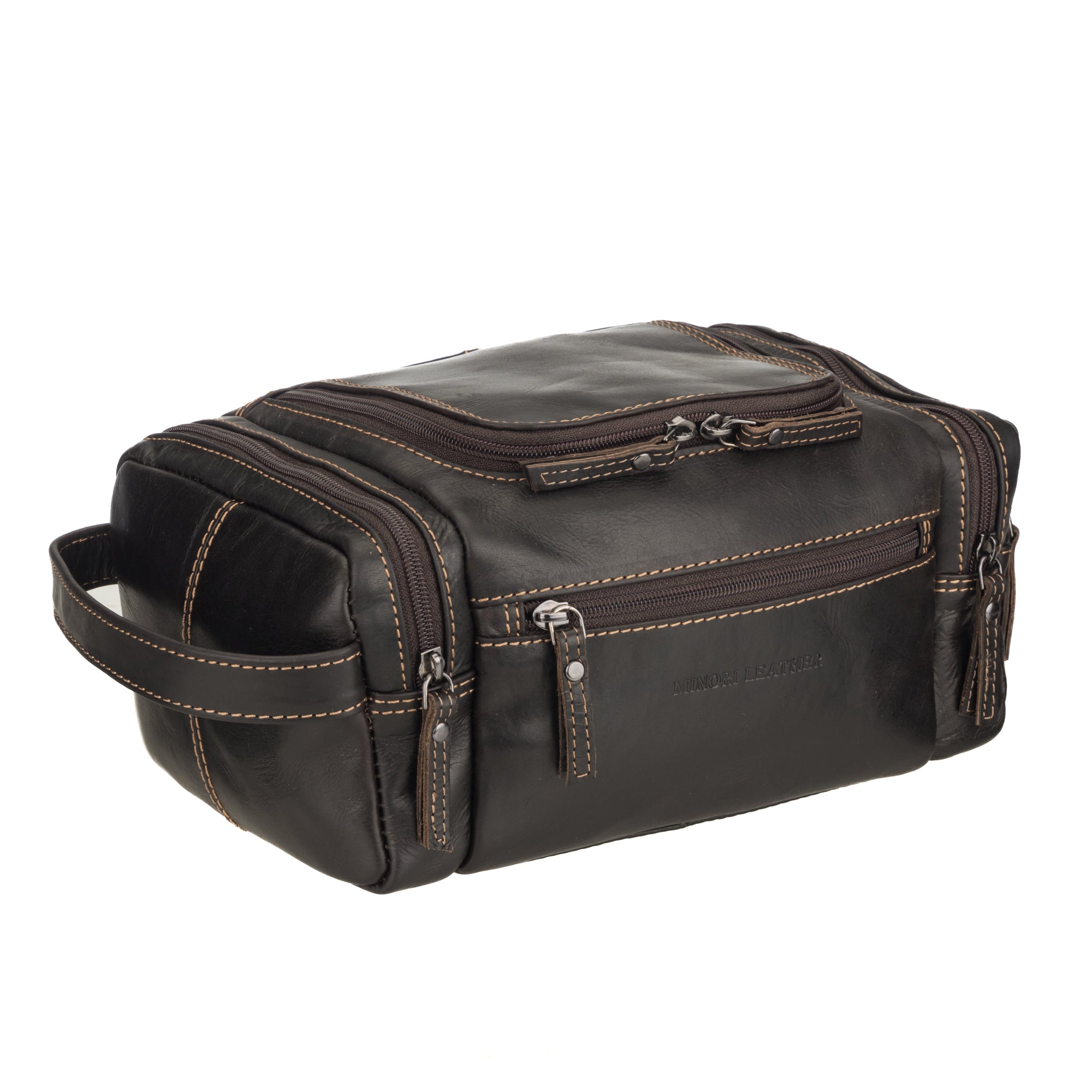 Angled front view of brown Minori leather toiletry bag showing side handle, front zipper pocket, and top dual-zippered main compartment.