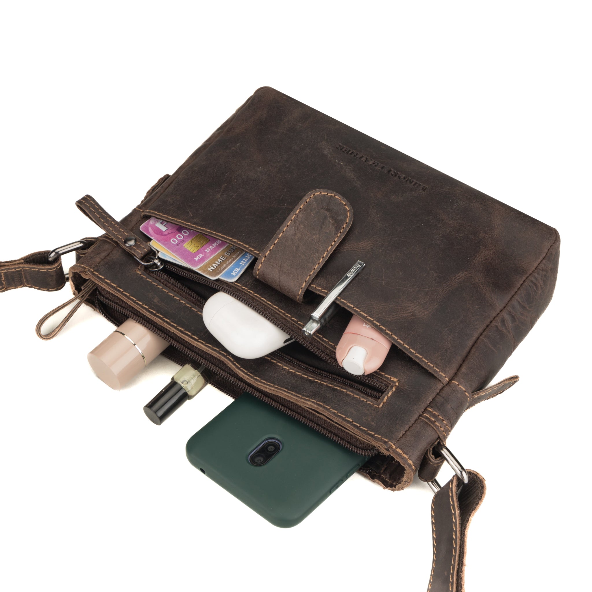 Brown Minori leather crossbody bag with phone, cards, and other items on a white background