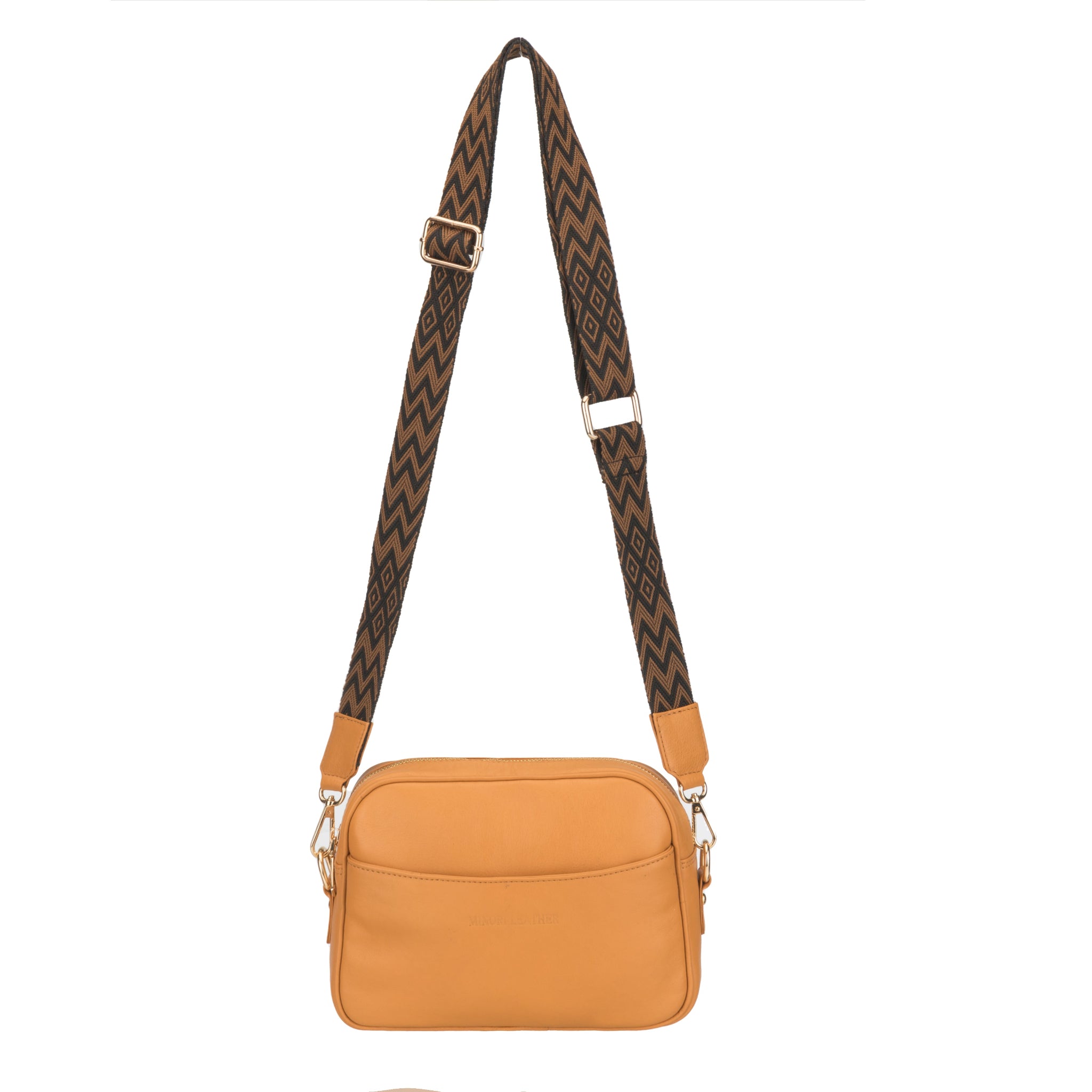 Tan Minori leather crossbody bag with a wide brown chevron-patterned strap displayed hanging against a white background.