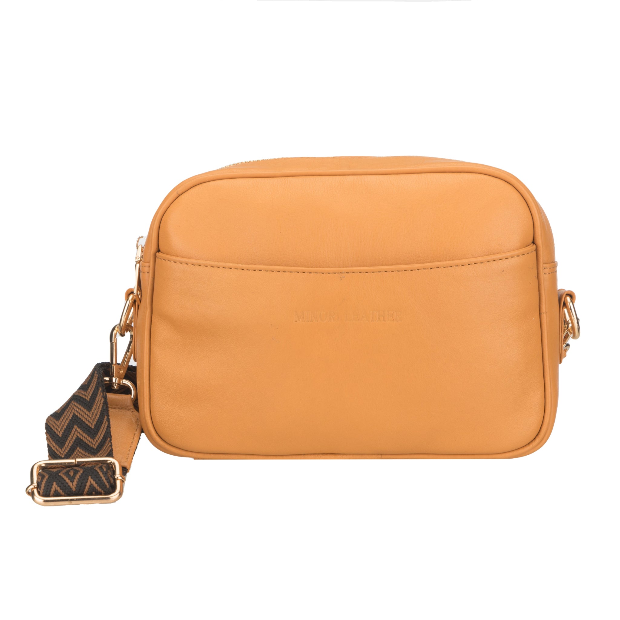 Front view of a tan Minori leather crossbody bag with curved front pocket and detachable zigzag strap.