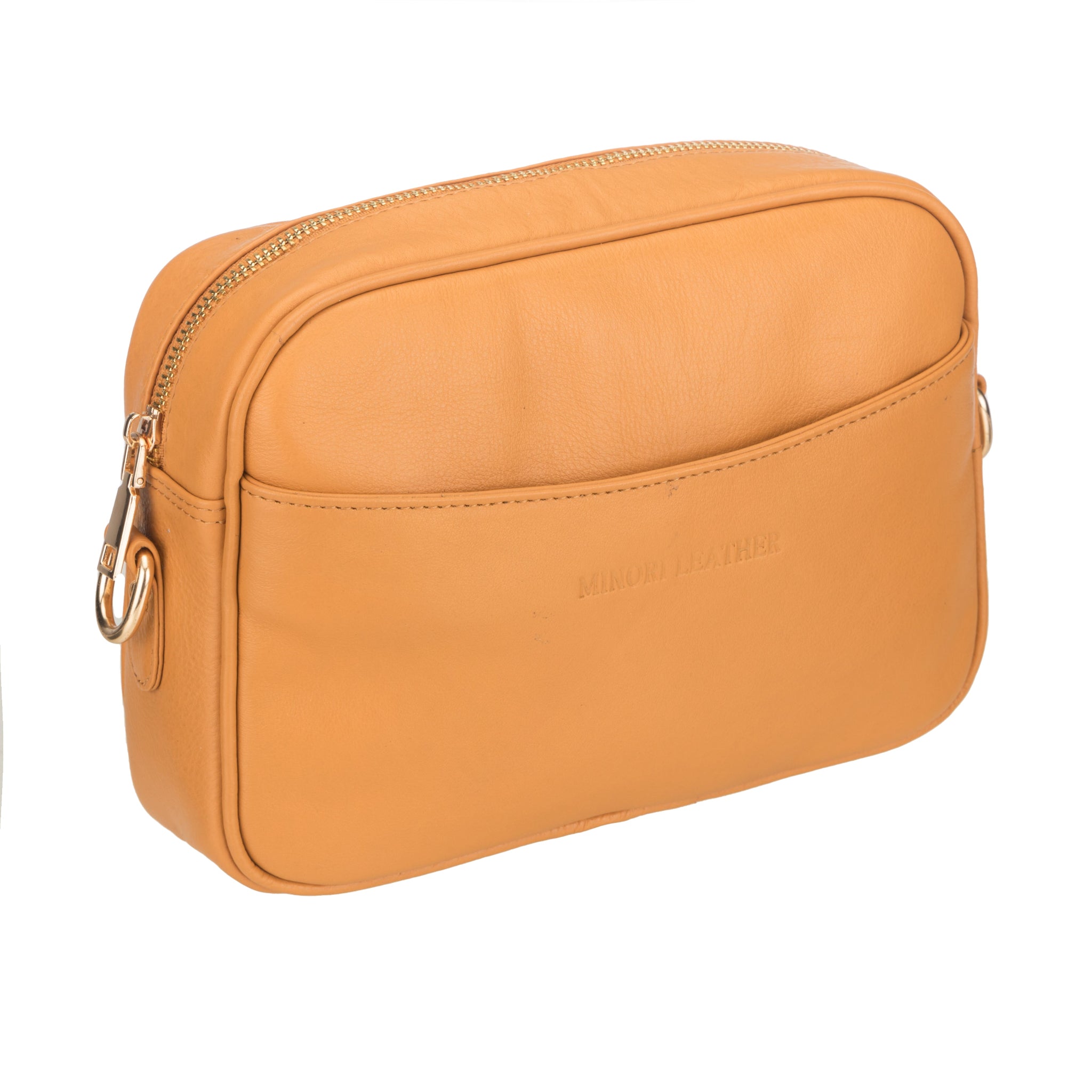 Angled view of a Tan Minori leather crossbody bag highlighting its smooth texture and gold zipper detailing.