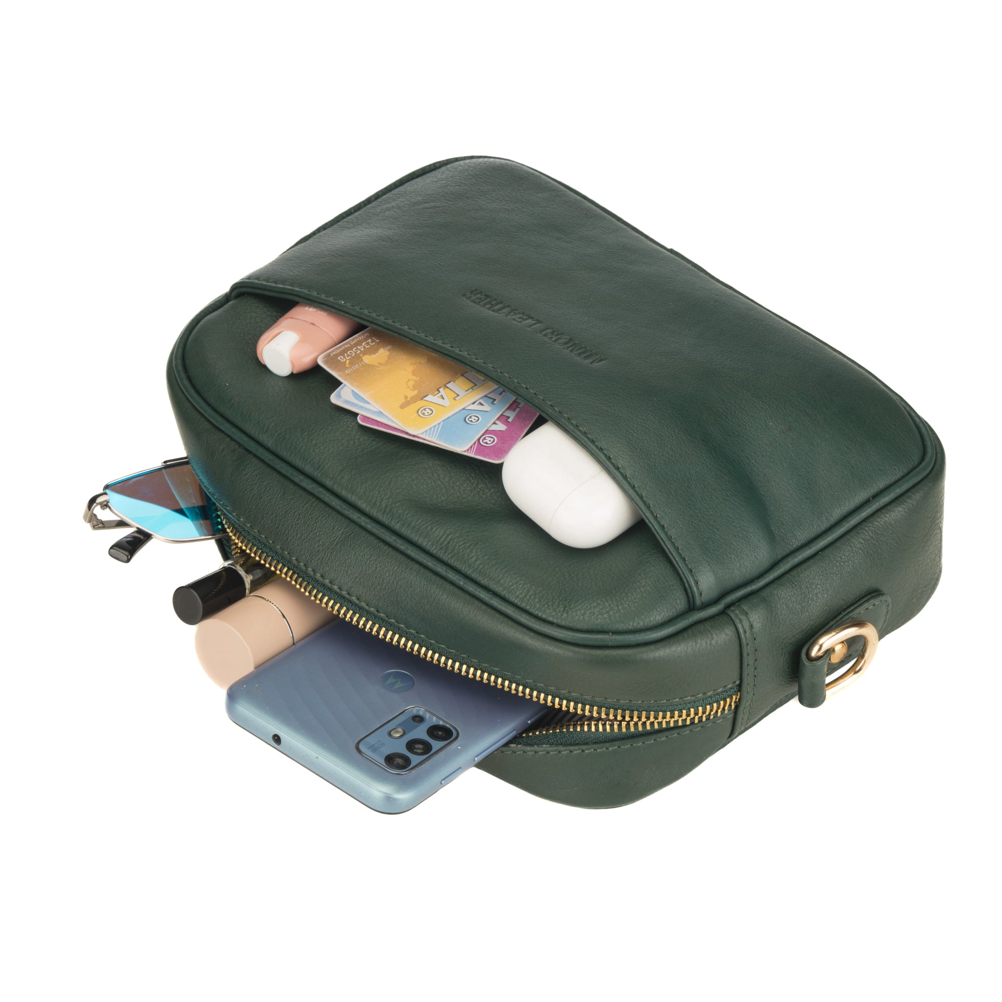 Forest Green Minori leather crossbody bag partially open and filled with daily essentials like cards, cosmetics, earphones, and a smartphone.