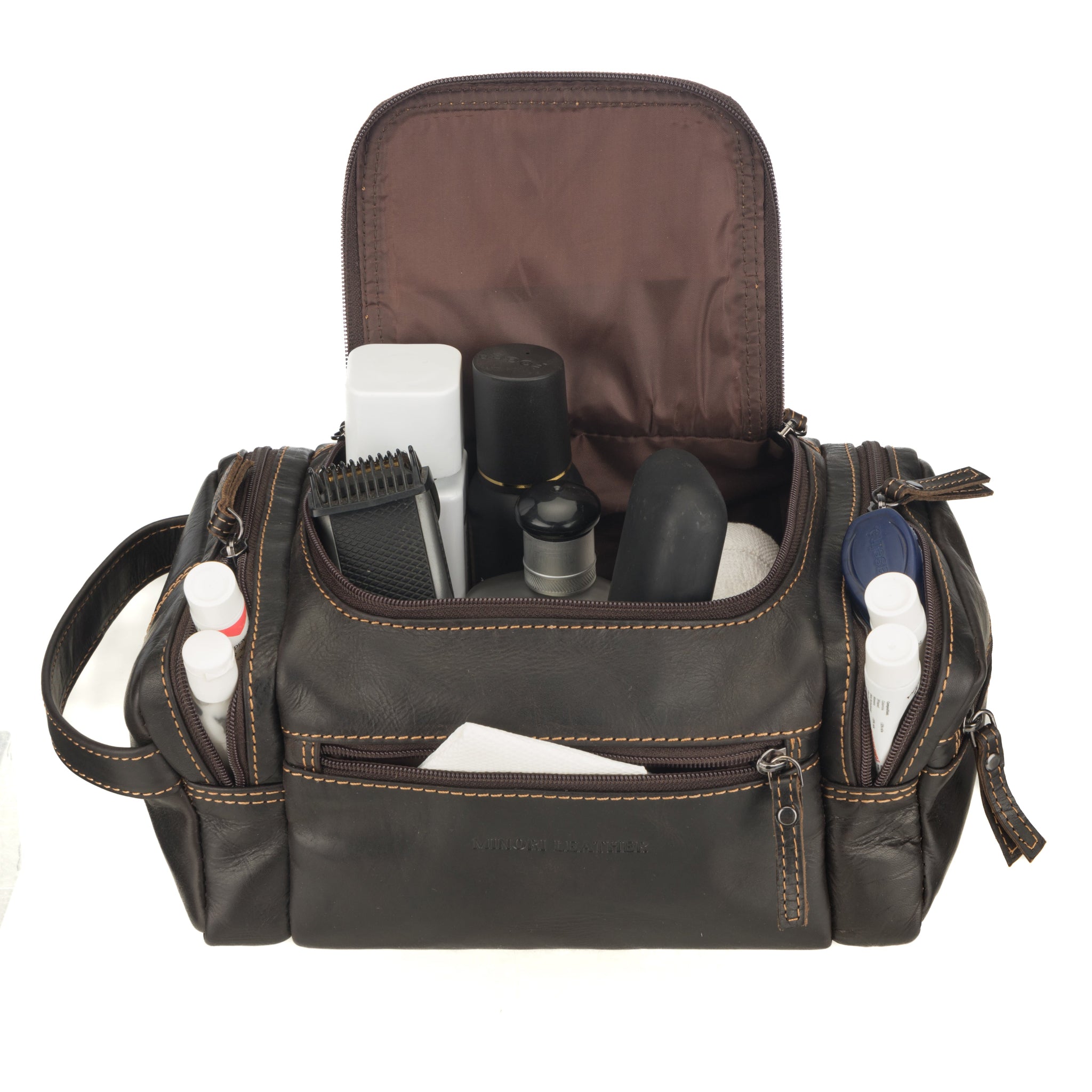 Brown Minori leather toiletry bag with compartments filled with grooming essentials including bottles, trimmer, and hygiene products, demonstrating storage capacity.