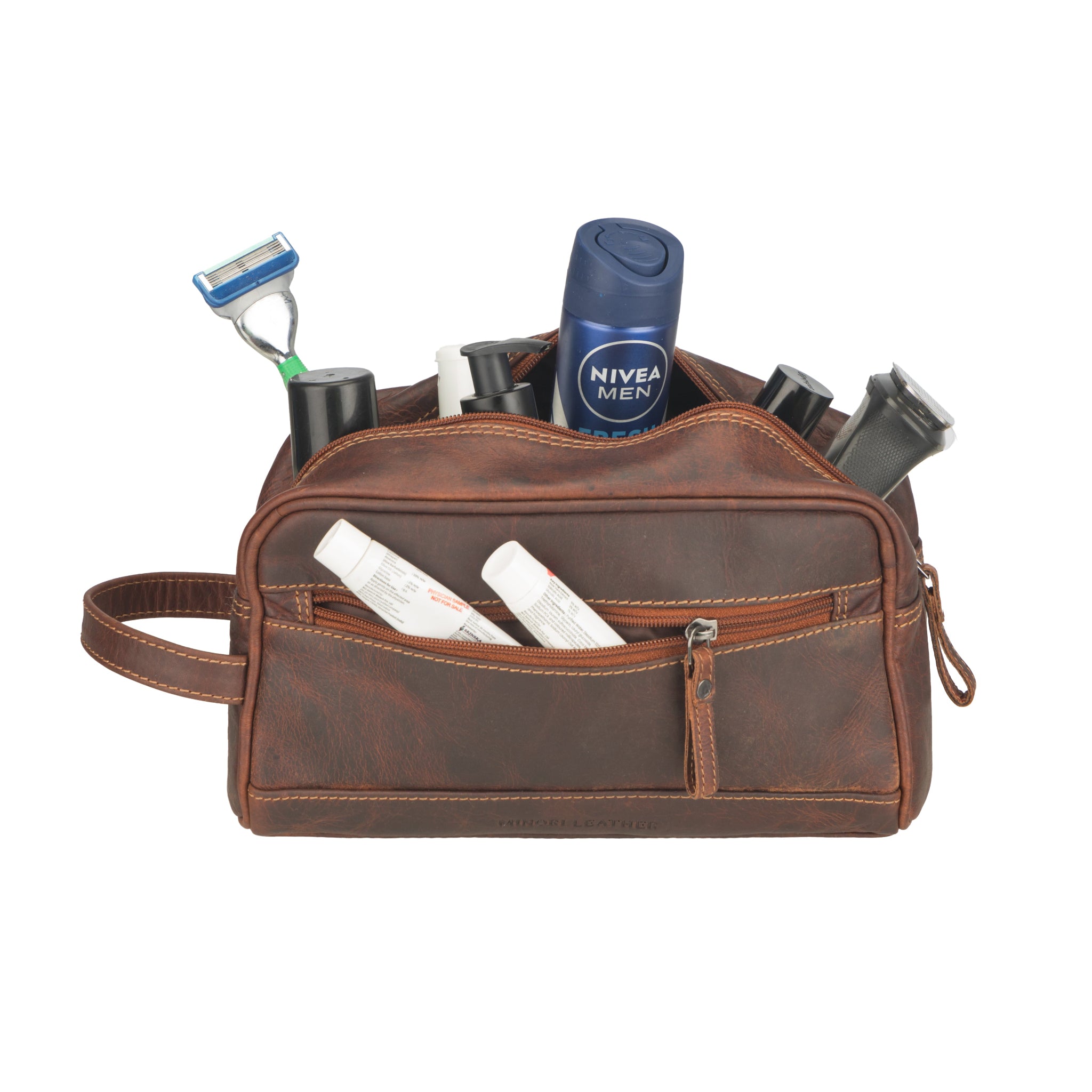 Brown Minori leather toiletry bag with grooming products on a white background