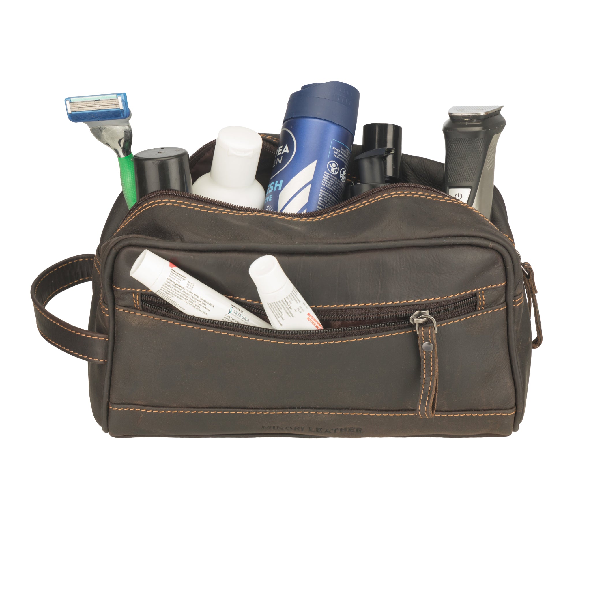 Brown Minori leather toiletry bag with various travel items on a white background