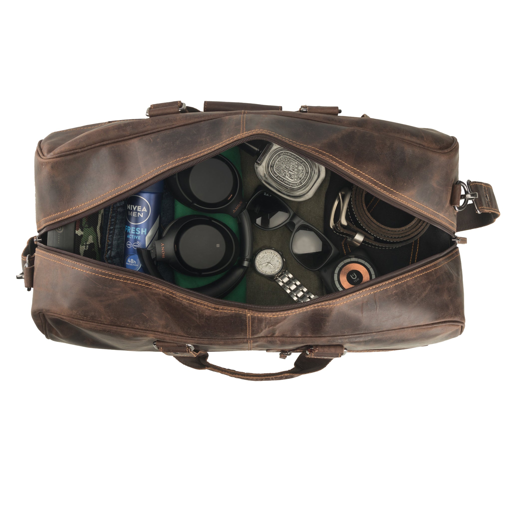 Top-down view of an open brown Minori leather duffle bag neatly packed with travel essentials, including headphones, deodorant, sunglasses, a watch, a belt, and grooming items.
