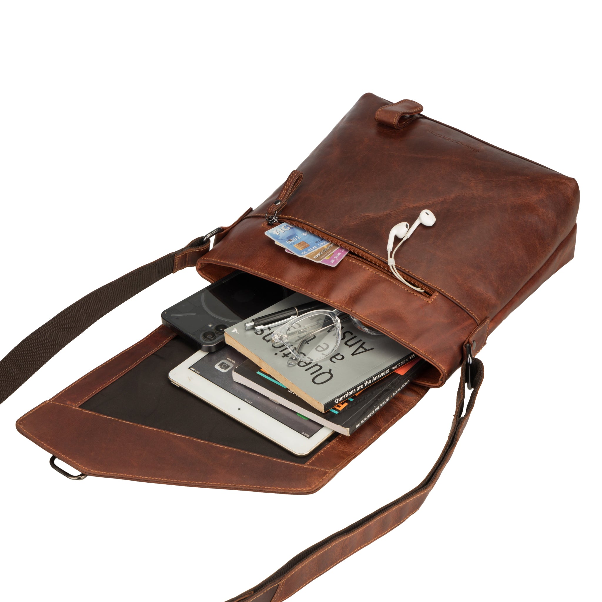 The Minori Leather bag opened to display its packed contents including an iPad, phone, wallet, and earbuds.