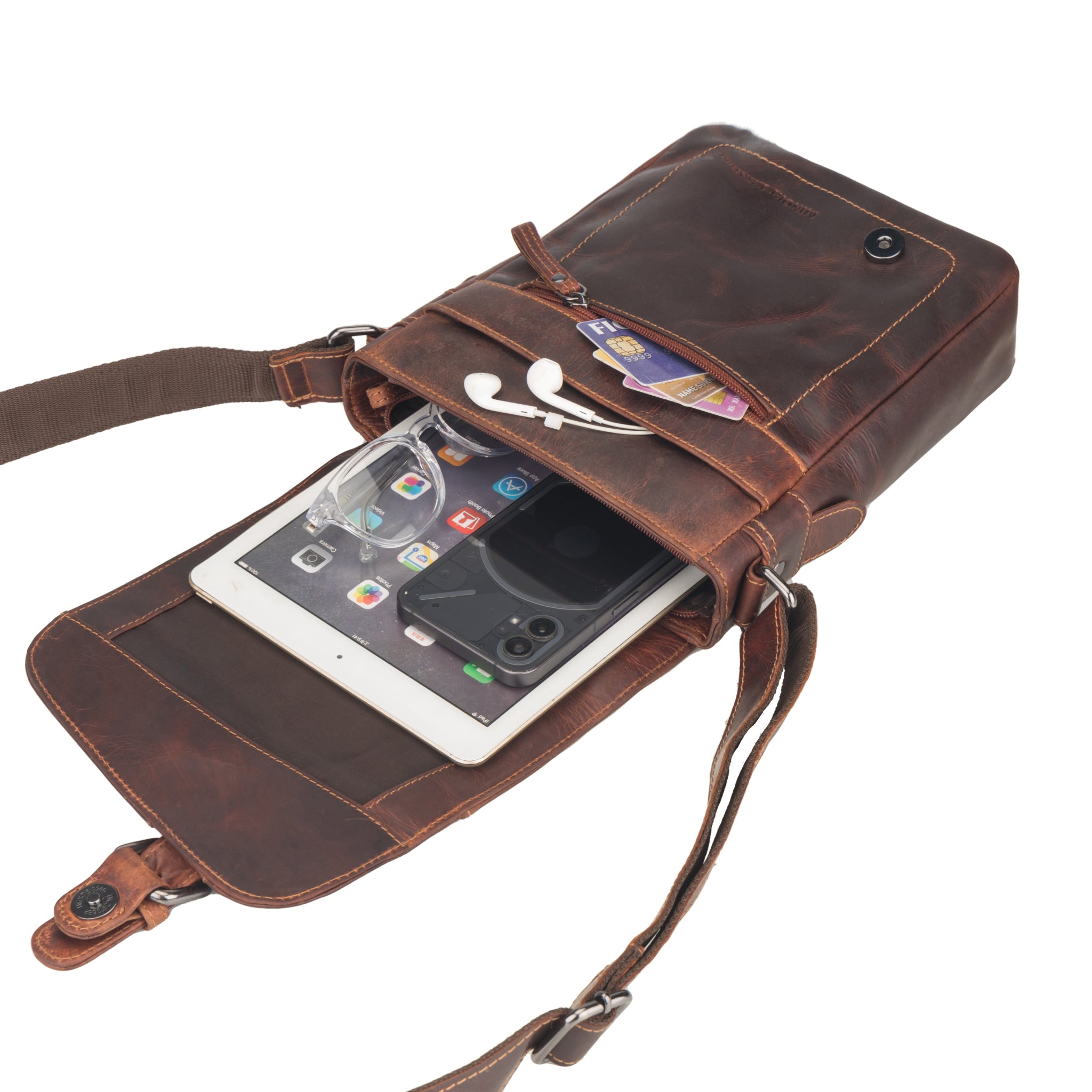 Contents inside the chestnut brown Minori leather crossbody bag showing an iPad, phone, glasses, and cards.