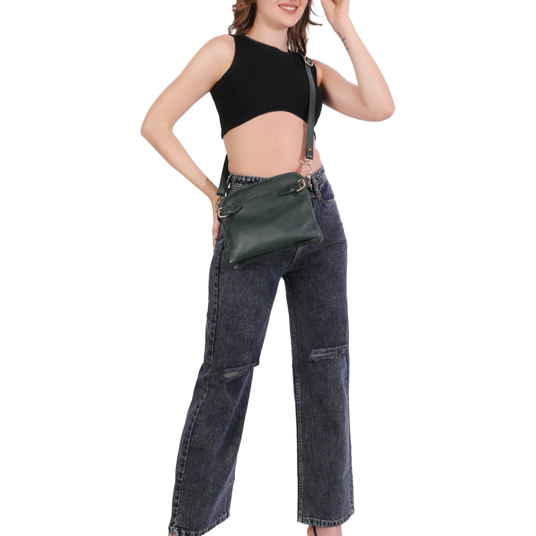 Woman wearing black sleeveless top and dark blue jeans on a white background carrying forest green Minori leather crossbody bag