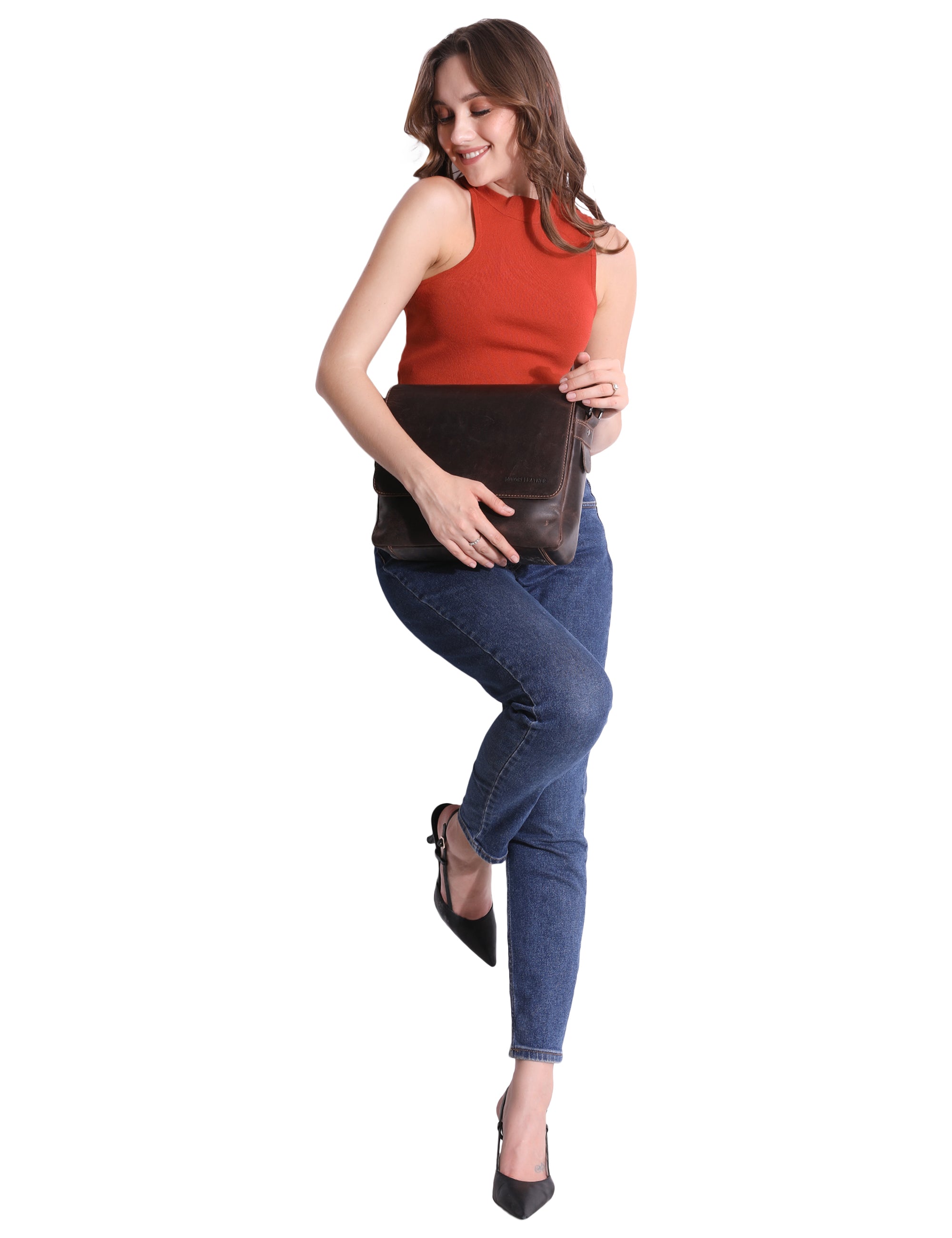 Woman wearing a red sleeveless top and blue jeans, holding a brown leather clutch against a white background