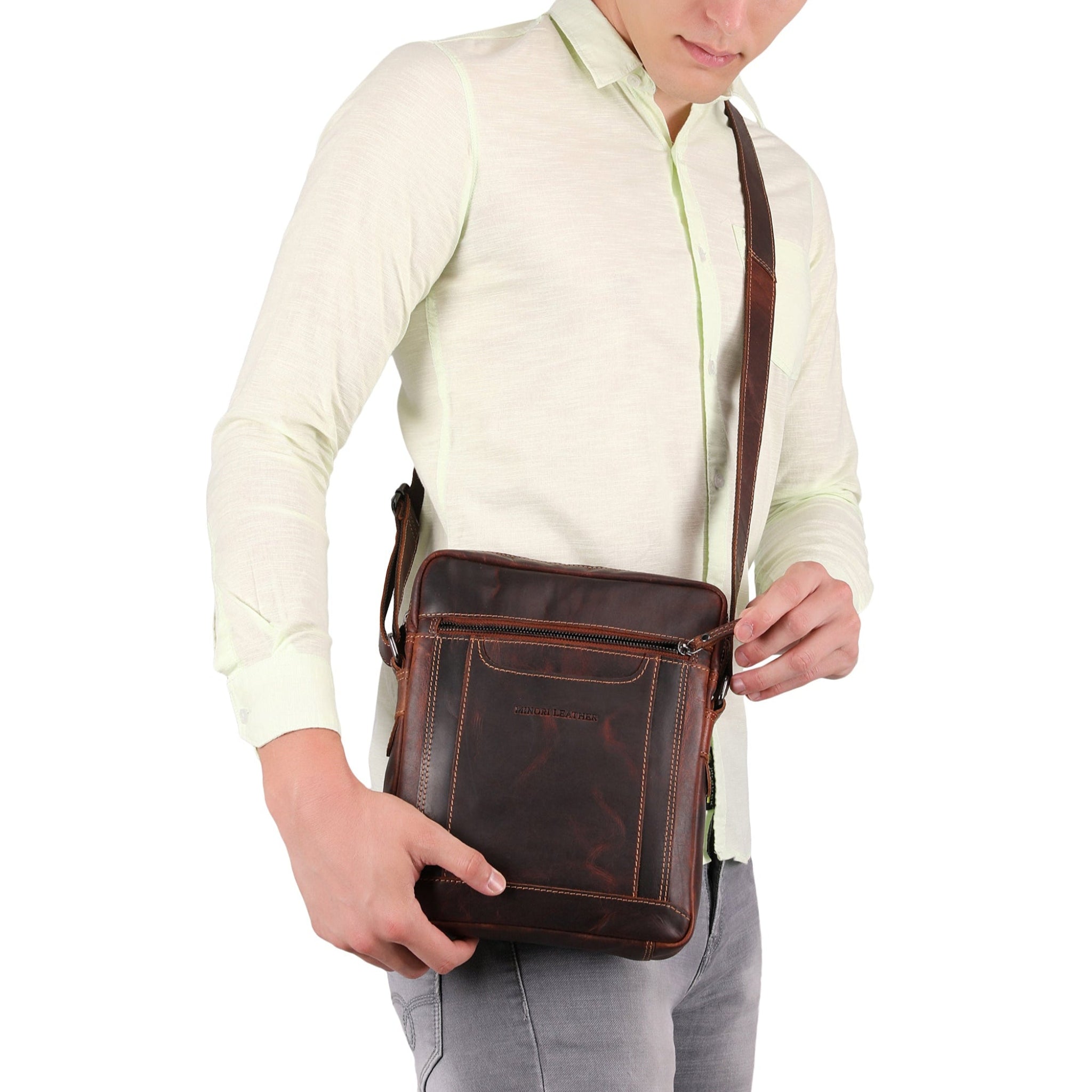 Man holding a brown Minori leather crossbody bag against a white background