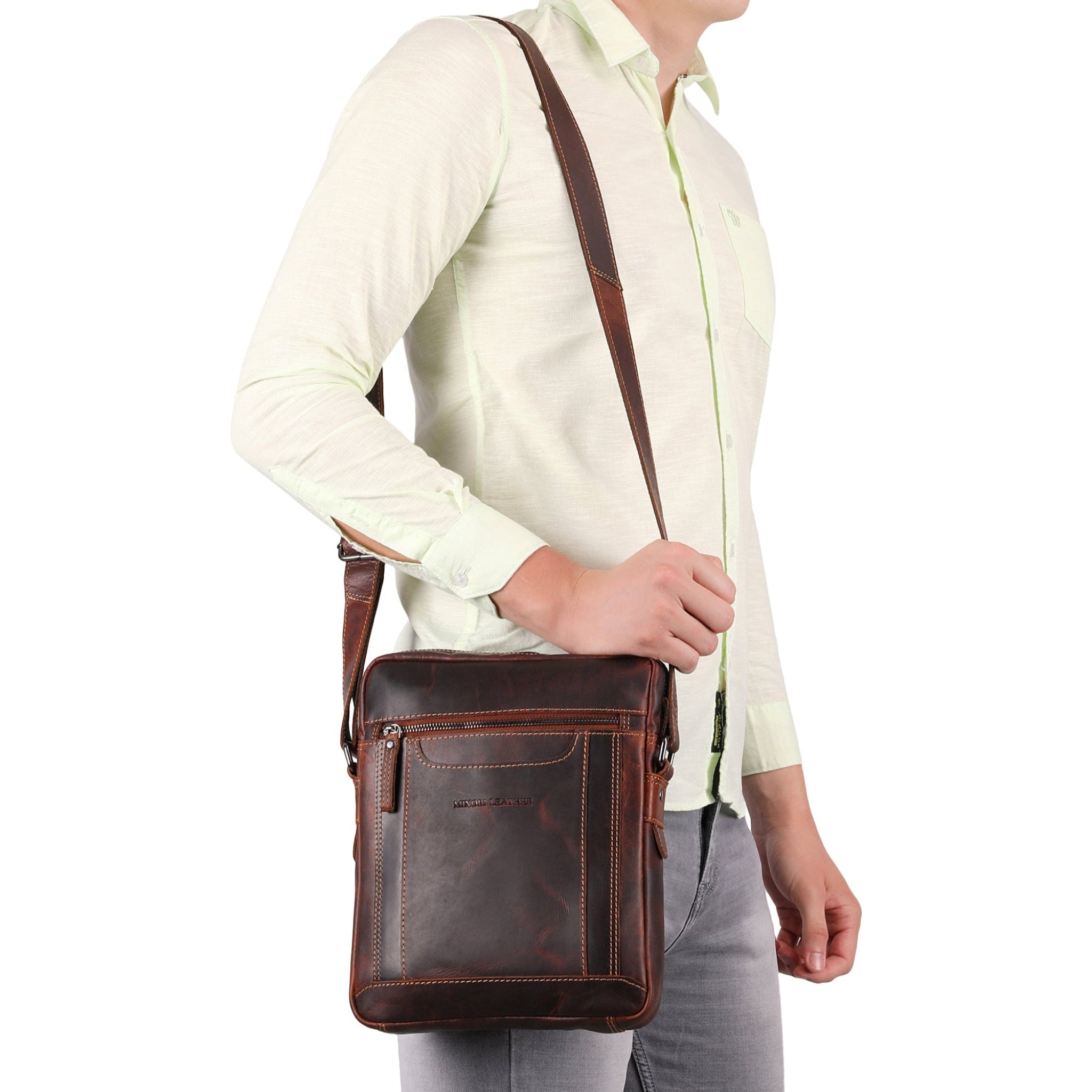 Person wearing a brown Minori leather shoulder bag on a white background