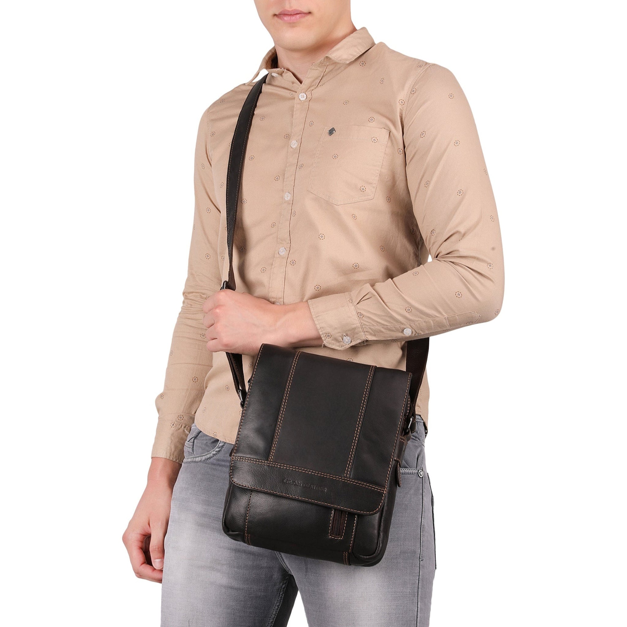 Person wearing a beige shirt and gray pants holding a Brown Minori leather bag on a white background