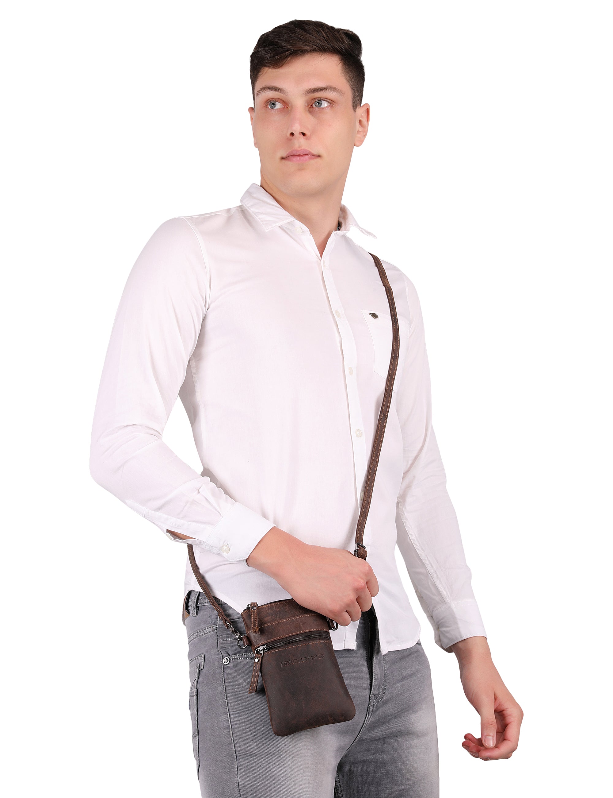 Man wearing a white shirt and gray pants with a brown Minori leather crossbody bag on a white background