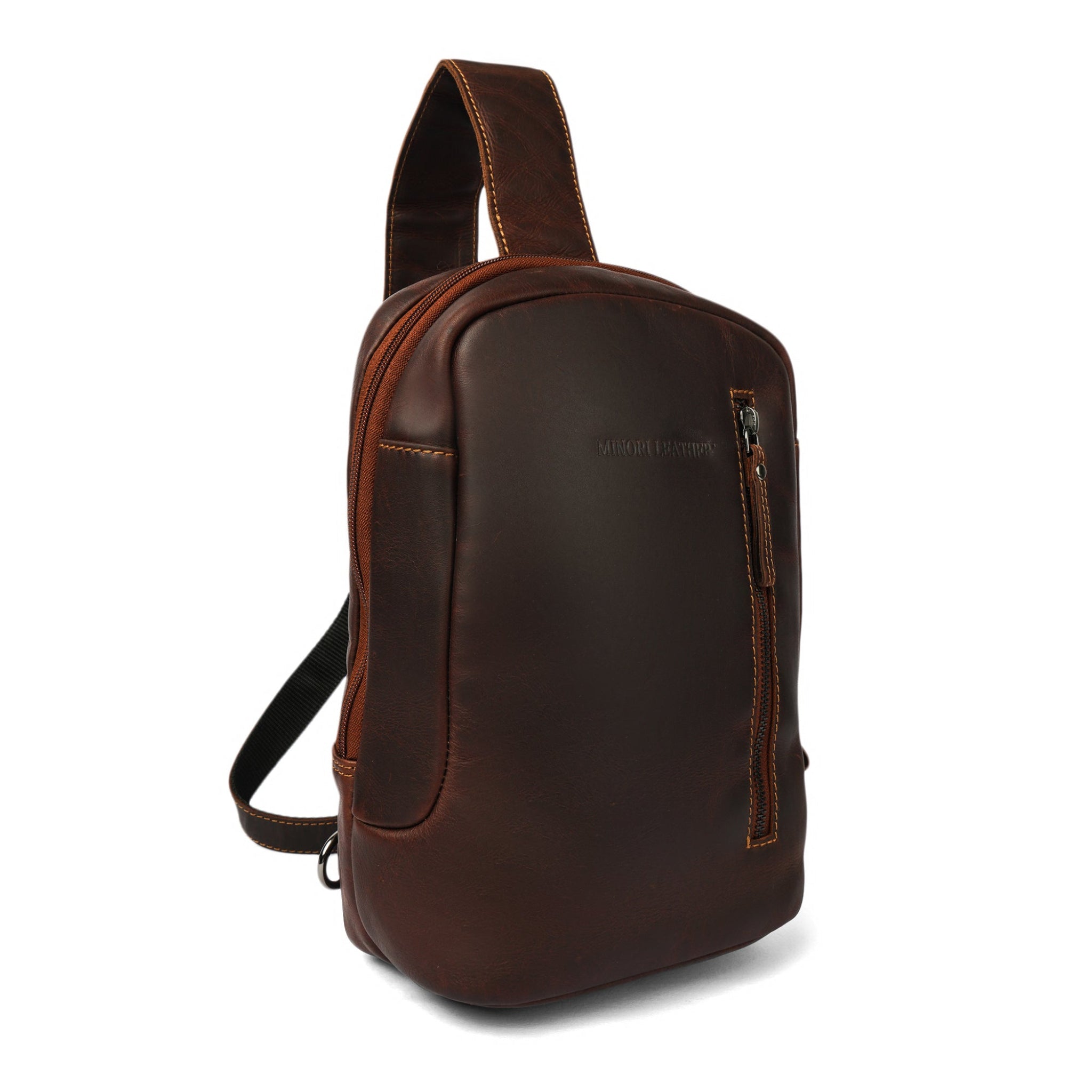 ide angle view of a brown Minori leather sling bag showing the main zipper and wide padded shoulder strap.