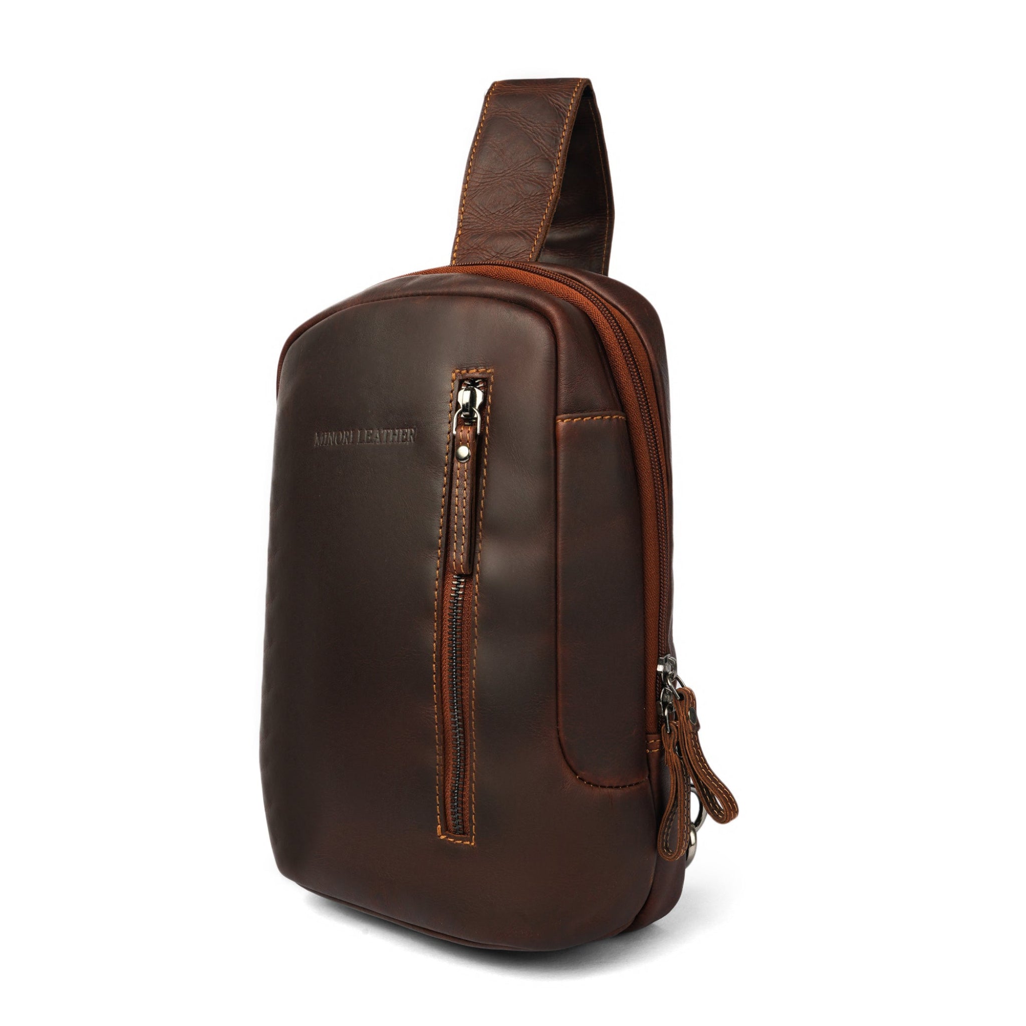 Angled front view of a brown Minori leather sling bag highlighting the compact structure and quality stitching.