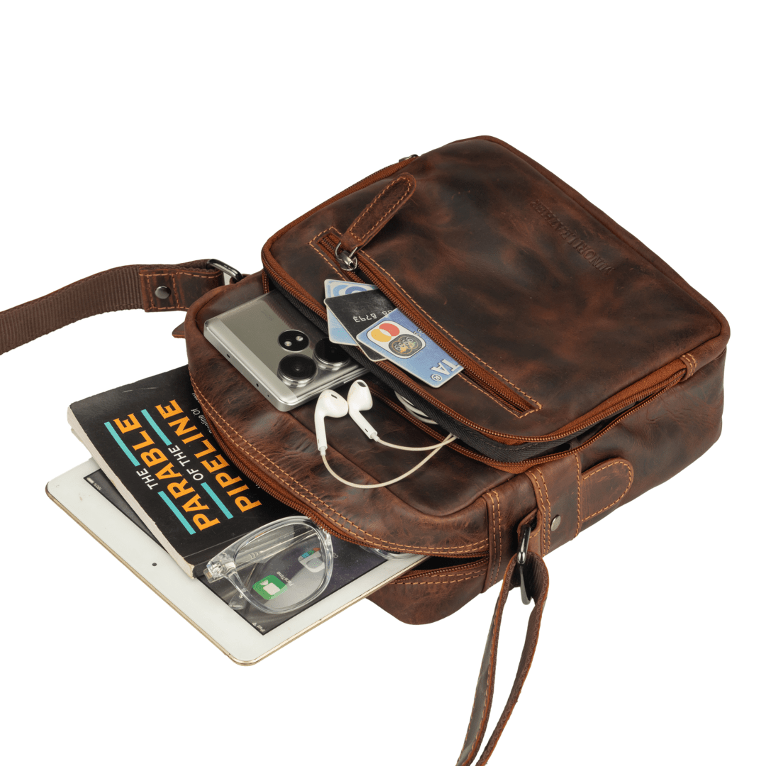 Minori Leather Harbor leather crossbody bag in chestnut with adjustable strap and sleek design, shown hanging on a hook.