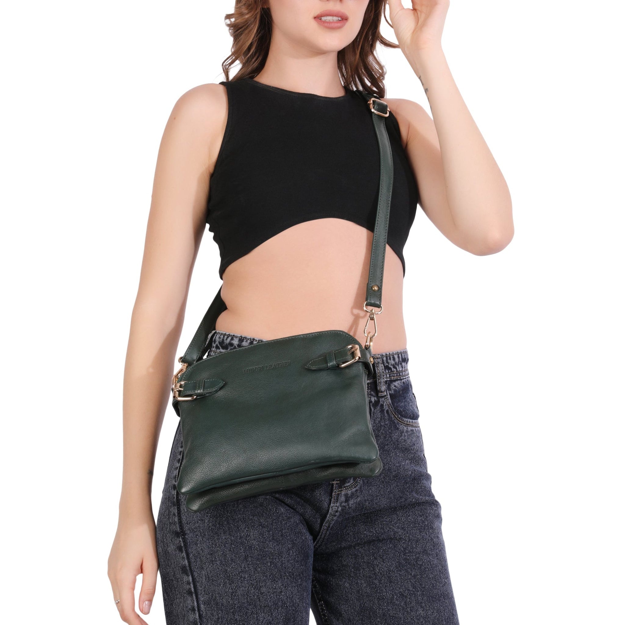 Forest Green Minori leather crossbody bag with gold-tone buckles and adjustable strap, worn across the body over casual outfit.