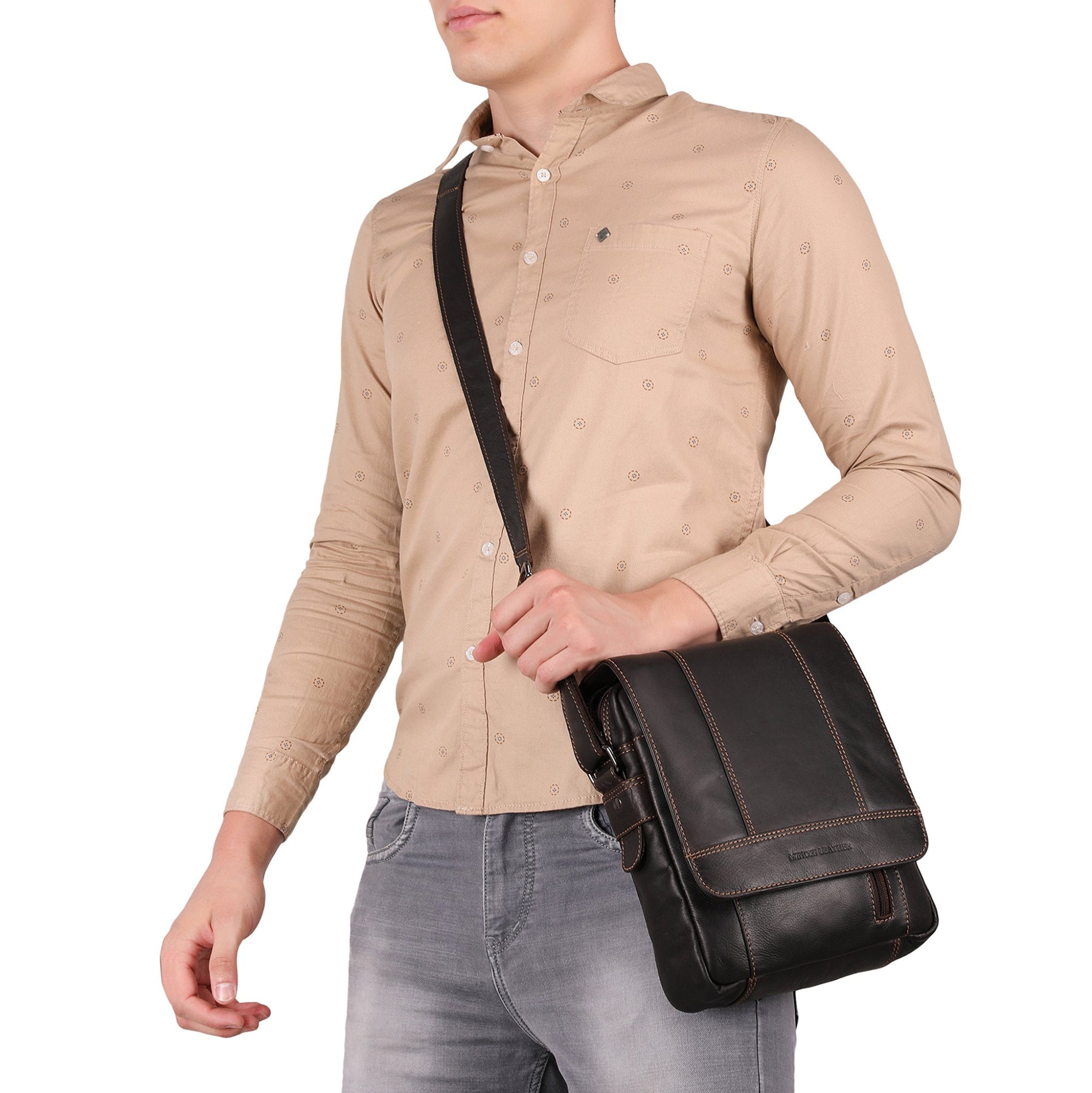 Man wearing a beige shirt and gray jeans holding a Brown Minori leather bag on a white background